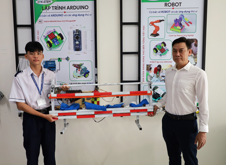 Lâm Đỗ Thiên Luân và thầy hướng dẫn bên mô hình Túi khí thông minh bên hông xe tải. Ảnh: QM uom-mam-nghien-cuu-khoa-hoc-3.jpg