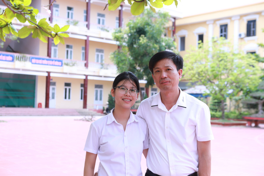 Ông Phạm Ngọc Chí và con cùng lưu giữ khoảnh khắc đáng nhớ bên mái trường Giao Thủy. Ảnh: Đình Tuệ. 1.jpg